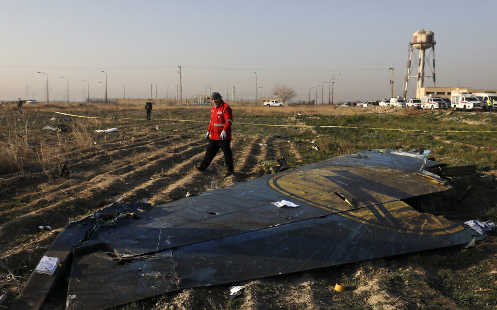 In this January 8, 2020, file photo a rescue worker searches the scene where a Ukrainian plane crashed in Shahedshahr southwest of the capital Tehran, Iran. (AP Photo/Ebrahim Noroozi, File)
