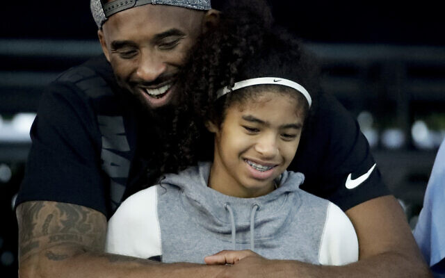 In this July 26, 2018 file photo former Los Angeles Laker Kobe Bryant and his daughter Gianna watch during the US national championships swimming meet in Irvine, Calif. Bryant, the 18-time NBA All-Star who won five championships and became one of the greatest basketball players of his generation during a 20-year career with the Los Angeles Lakers, died in a helicopter crash Sunday, Jan. 26, 2020. Gianna also died in the crash. She was 13. (AP Photo/Chris Carlson)
