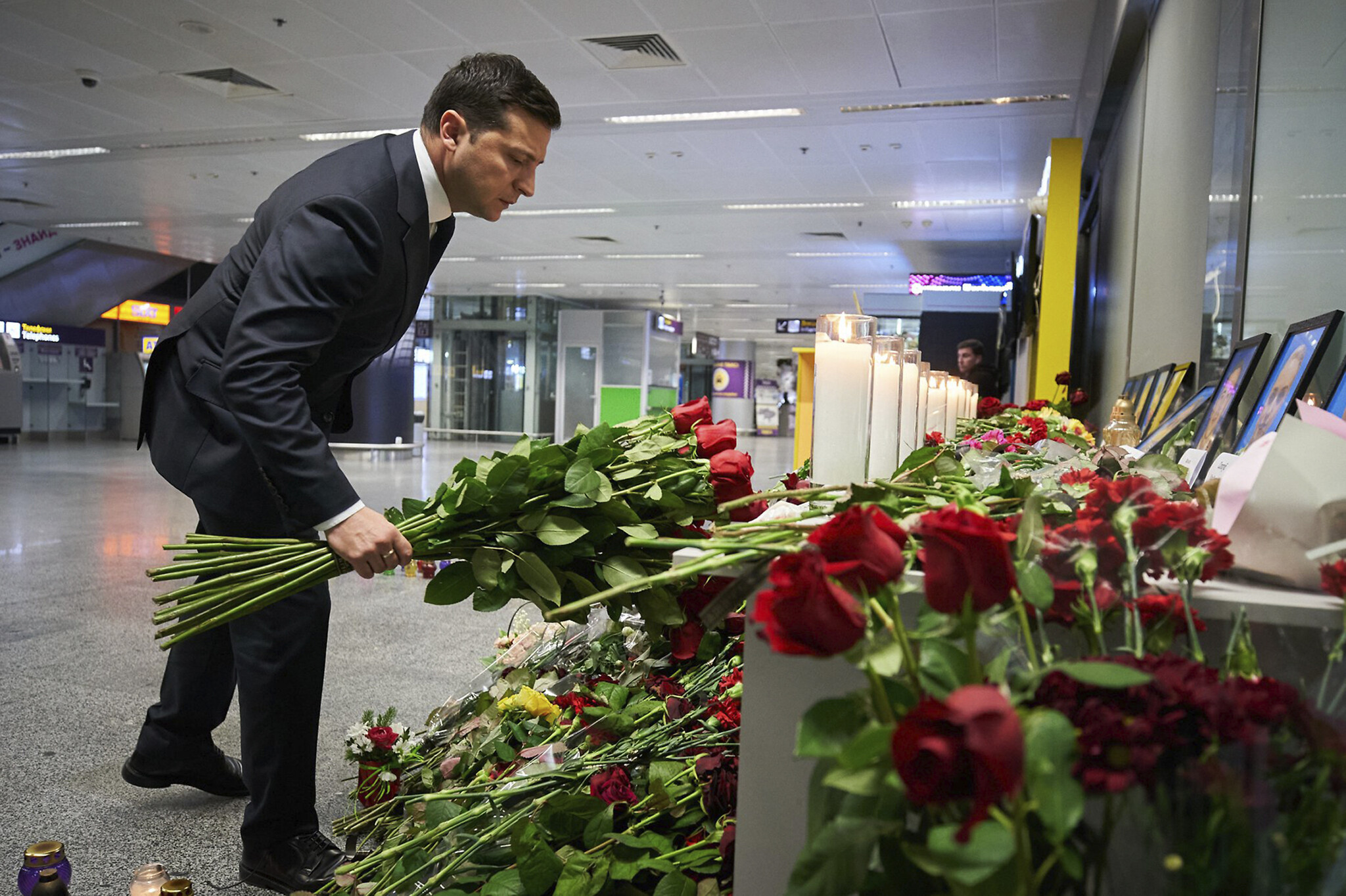 Ukrainian President Volodymyr Zelensky lays flowers at a memorial of the flight crew members of the Ukrainian 737-800 plane that crashed on the outskirts of Tehran, at Borispil international airport outside in Kyiv, Ukraine, January 9, 2020. (Ukrainian Presidential Press Office via AP)