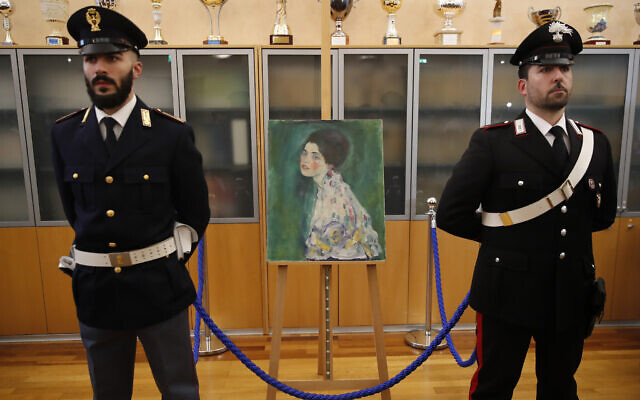 An Italian Policeman, left, and a Carabiniere, paramilitary police officer, stand beside a painting which was found last December near an art gallery and believed to be the missing Gustav Klimt's painting ‘Portrait of a Lady’ during a press conference in Piacenza, Italy, Jan. 17, 2020 (AP Photo/Antonio Calanni)