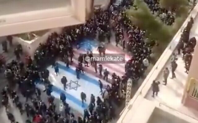 Screen capture from video apparently showing Iranian anti-regime protesters refusing to walk across US and Israeli flags at a demonstration at a Tehran university, January 12, 2020. (Twitter)