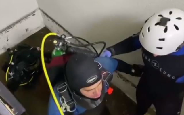 Divers seen inside a Tel Aviv building where a man and woman died Saturday due to the flooding of a basement level (Channel 13 screenshot)
