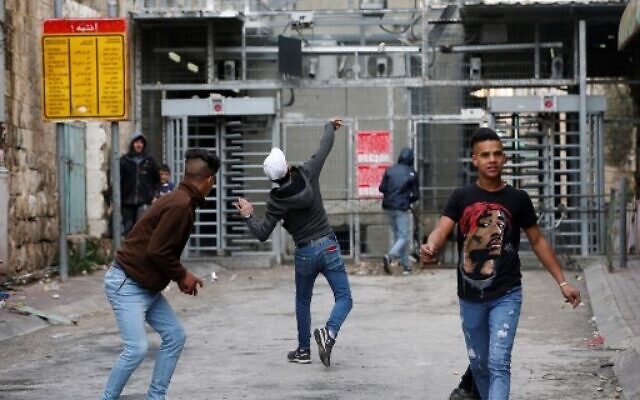 Palestinians throw stones at an Israeli checkpoint during clashes with Israeli forces in the center of the flashpoint city of Hebron in the West Bank on February 4, 2020. (Photo by HAZEM BADER / AFP)
