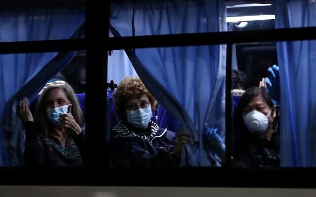 US passenger wave to reporters as they leave the Daikaku Pier Cruise Terminal in Yokohama port, next to the Diamond Princess cruise ship, with people quarantined onboard due to fears of the new COVID-19 coronavirus, at on February 17, 2020. (Behrouz MEHRI / AFP)