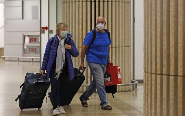 Passengers wearing protective masks walk at the arrival hall of Ben Gurion International Airport on February 22, 2020.  (Ahmad GHARABLI/AFP)