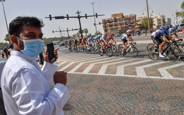 A man wearing a surgical masks looks on as the pack rides by during stage five the UAE Cycling Tour from al-Maroom to Jebel Hafeet, in Dubai on February 27, 2020. (Giuseppe CACACE / AFP)