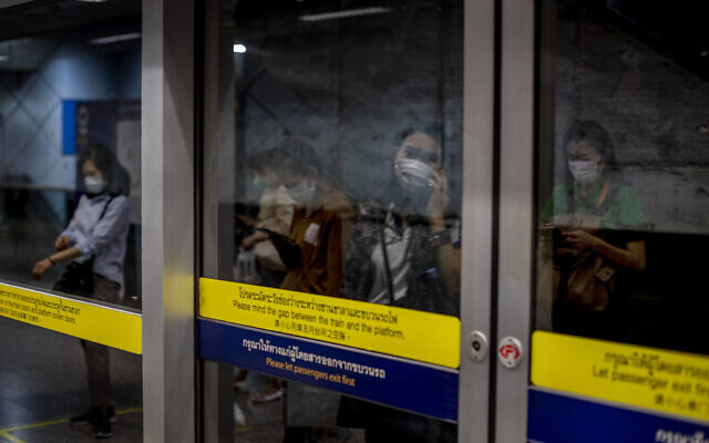 Commuters wearing face masks are mirrored in a subway station in Bangkok, Thailand, February 19, 2020. (AP Photo/Gemunu Amarasinghe)