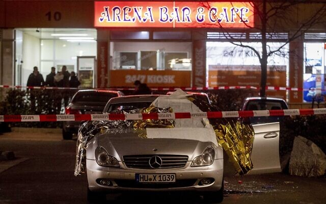 A car with covered dead bodies stands in front of a bar in Hanua, Germany Thursday, Feb. 20, 2020. German police say several people were shot to death in the city of Hanau on Wednesday evening. (AP Photo/Michael Probst)
