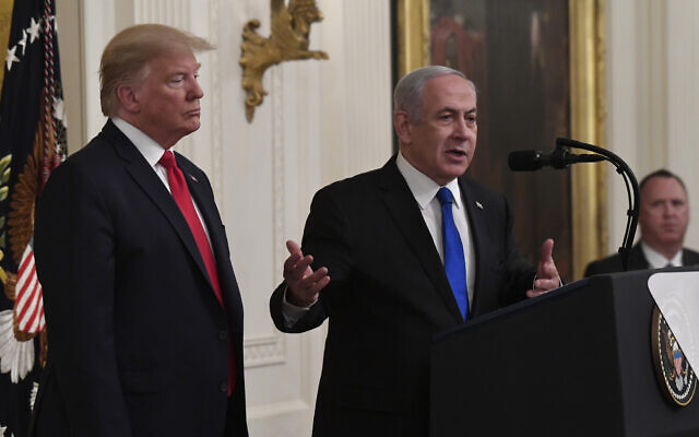 US President Donald Trump, left, listens as Prime Minister Benjamin Netanyahu, right, speaks during an event in the East Room of the White House in Washington, January 28, 2020, to announce the Trump administration’s much-anticipated plan to resolve the Israeli-Palestinian conflict. (AP Photo/Susan Walsh)