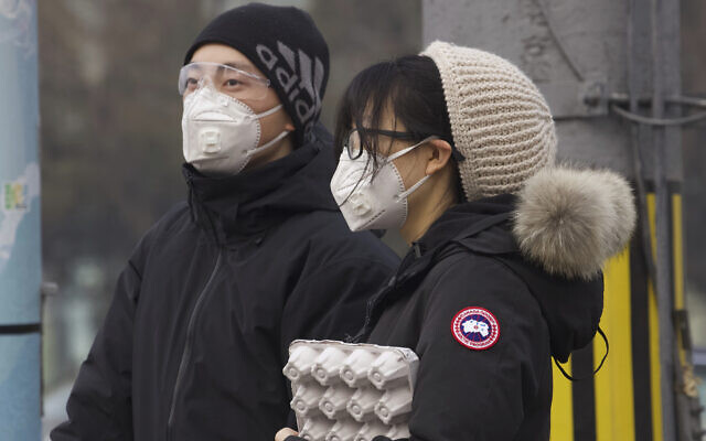 Los residentes con máscaras esperan en un semáforo en Beijing, China, el 13 de febrero de 2020. (Foto AP / Ng Han Guan)