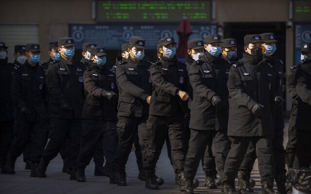 Policemen wear face masks as they march in formation outside the Beijing Railway Station in Beijing, February 15, 2020 (AP Photo/Mark Schiefelbein)