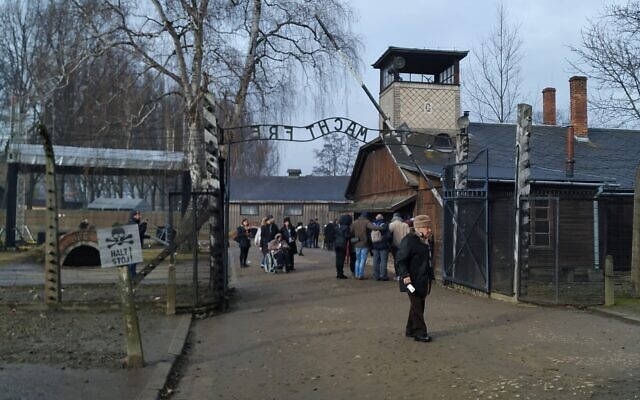 Visitors walk through the infamous gate reading 'Arbeit Macht Frei,' or 'work sets you free,' at the former site of Auschwitz-Birkenau, January 28, 2020. (Yaakov Schwartz/Times of Israel)