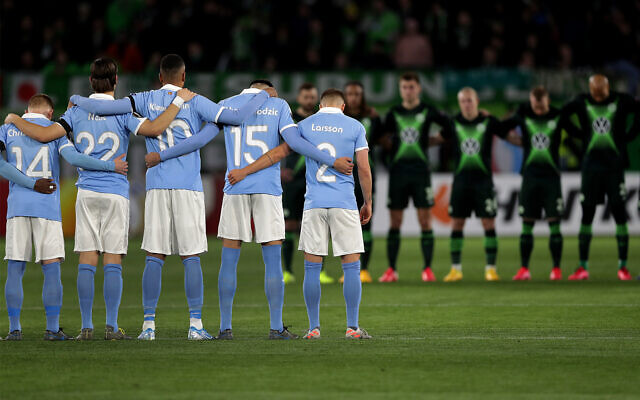 Players from Wolfsburg, rear, and Malmo, front, hold a minute of silence for the victims of the deadly attack in the German city of Hanau prior to a soccer match between VfL Wolfsburg and Malmo FF in Wolfsburg, Germany, Feb. 20, 2020. (AP Photo/Michael Sohn)