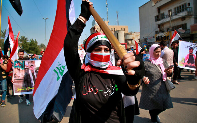 An anti-government protester holds an Iraqi flag during demonstrations in Baghdad, Iraq, Feb. 23, 2020. (AP Photo/Khalid Mohammed)
