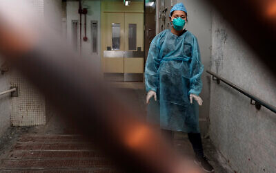 A medical worker wearing a protective suit waits near an entrance of a public housing estate during an evacuation of residents amid a coronavirus outbreak in Hong Kong, February 11, 2020. (AP Photo/Kin Cheung)