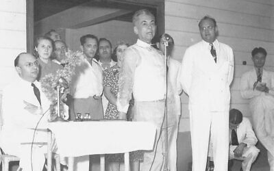 Philippines president Manuel L. Quezon (center at mic) welcoming Jewish refugees April 23, 1940 at the dedication of Marikina Hall, which he constructed on his own property to house the newly arrived immigrants. To his left is Alex Frieder (white suit/seated), chairman of the Philippines Jewish Refugee Committee, and to the right (white suit/standing) is Herbert Frieder. (Courtesy 'Rescue in the Philippines')