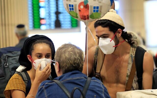 A young couple wearing protective masks are greeted upon arrival at Ben Gurion Airport on March 4, 2020 (Emmanuel DUNAND / AFP)