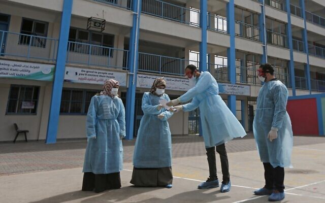 Palestinian health workers wearing  protective face maskS are pictured in the courtyard of a United Nations Relief and Works Agency for Palestinian Refugees (UNRWA) school at al-Shati refugee camp in Gaza City on March 18, 2020, as preparations are underway to receive, examine and isolate victims of the Covid-19 coronavirus. (MAHMUD HAMS / AFP)