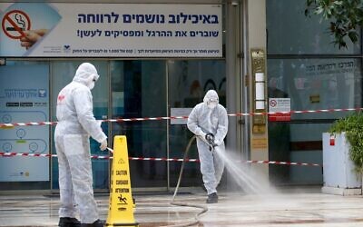 An Israeli firefighter sprays disinfectant at the entrance of the Tel Aviv Sourasky Medical Center in Tel Aviv on March 20, 2020. (JACK GUEZ / AFP)