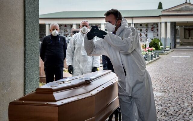 Illustrative: A pallbearer takes a picture of a coffin for the relatives of a deceased person at the cemetery of Grassobbio in the province of Bergamo, as they could not attend the ceremony because they are in quarantine as a result of the novel coronavirus, March 23, 2020 . (Piero Cruciatti/AFP)