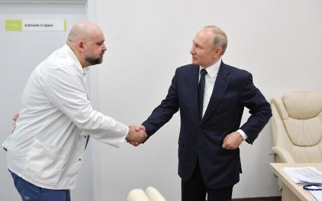 A picture taken on March 24, 2020 shows Russian President Vladimir Putin, right, shaking hands with the head of Moscow's new hospital treating coronavirus (COVID-19) patients, Denis Protsenko, during his visit to Kommunarka hospital in Moscow. (Alexey DRUZHININ / SPUTNIK / AFP)