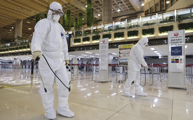 Workers wearing protective suits spray disinfectant as a precaution against the coronavirus at the Gimpo Airport in Seoul, South Korea, Tuesday, March 10, 2020. (Lee Ji-eun/Yonhap via AP)
