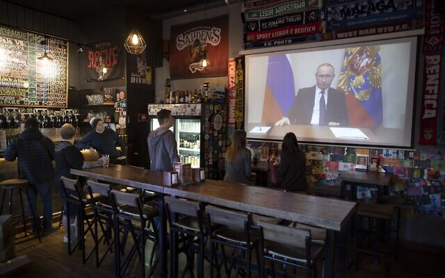 A few visitors and staff of the pub watching the broadcast of Russian President Vladimir Putin addresses Russian citizens on the State Television channels in Moscow, Russia, on March 25, 2020. (Alexander Zemlianichenko/AP Photo)