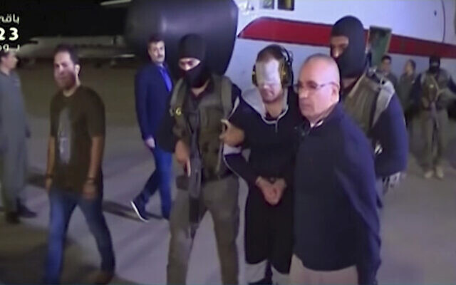 In this frame grab from Egyptian State Television, a blindfolded Hisham el-Ashmawi is escorted by Egyptian military officers and placed in a vehicle after being taken off a military plane at an airport in Cairo, Egypt, May 29, 2019 (Egyptian State Television via AP)