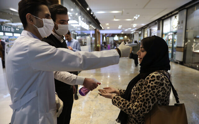 A woman has her temperature checked and her hands disinfected as she enters the Palladium Shopping Center in northern Tehran, Iran, March 3, 2020. (Vahid Salemi/AP)