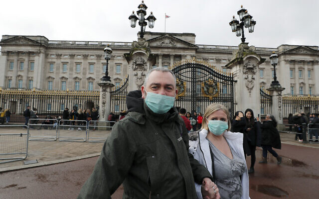 A couple wear face masks as they visit Buckingham Palace in London, March 14, 2020 (AP Photo/Frank Augstein)
