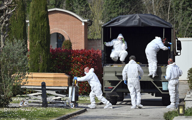 A convoy of Italian Army trucks is unloaded upon arrival from Bergamo carrying bodies of coronavirus victims to the cemetery of Ferrara, Italy, where they were to be cremated, Saturday, March 21, 2020. (Massimo Paolone/LaPresse via AP)