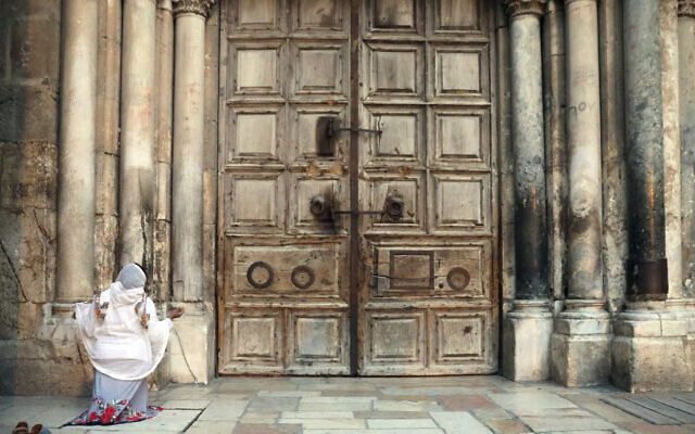 A woman prays in front of the closed Church of the Holy Sepulchre, in the Old City of Jerusalem, March 25, 2020. (Mahmoud Illean/AP)