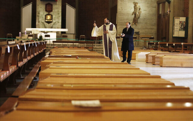 Don Marcello Crotti, left, blesses the coffins with Don Mario Carminati in the San Giuseppe church in Seriate, Italy, March 28, 2020  (AP Photo/Antonio Calanni)