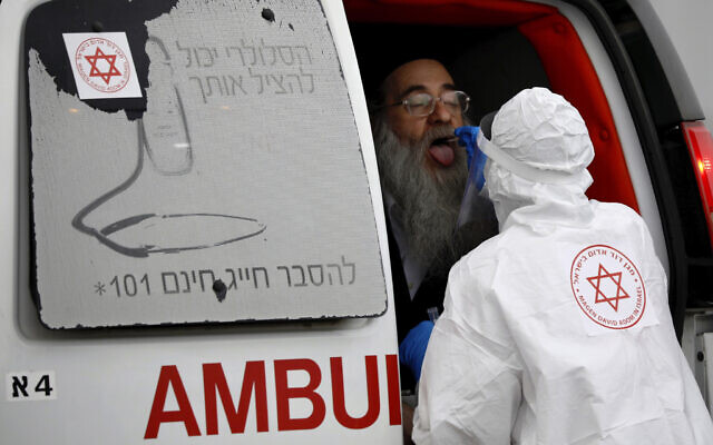 A medical worker wearing protective gear takes a swab from an ultra-Orthodox Jewish man for a coronavirus test in Bnei Brak, March 31, 2020. (AP Photo/Ariel Schalit)