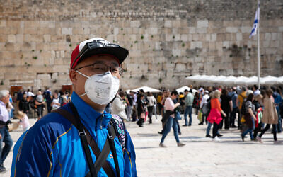A tourist wears a face mask for protection from the coronavirus at he Western Wall in the Old City of Jerusalem, February 27, 2020. (Olivier Fitoussi/Flash90)