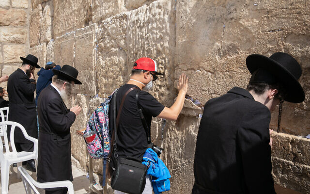 Un turista con una máscara facial por miedo al coronavirus, reza en el Muro de los Lamentos en la Ciudad Vieja de Jerusalén el 27 de febrero de 2020 (Olivier Fitoussi / Flash90)