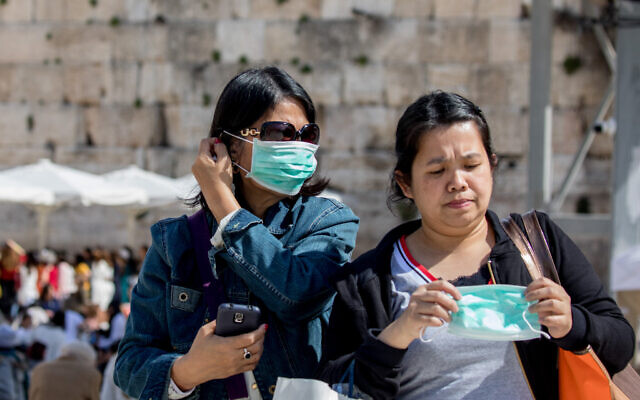 Tourists wearing face masks for fear of the coronavirus tours at the Western Wall in the Old City of Jerusalem on March 5, 2020. (Olivier Fitoussi/Flash90)