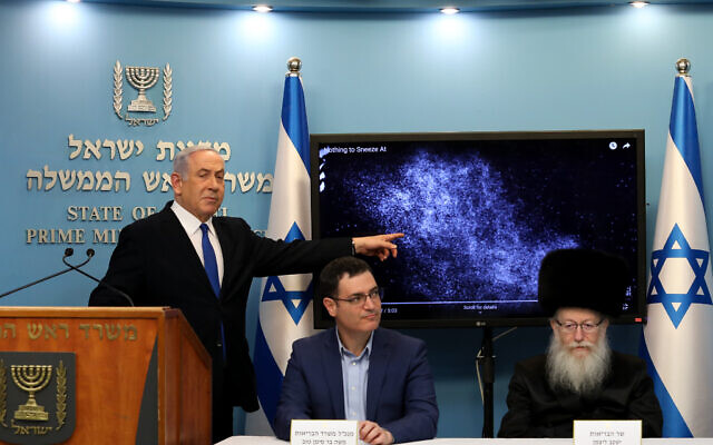 Israeli Prime Minister Benjamin Netanyahu with Health Minister Yaakov Litzman (right) and Health Ministry General Manager Moshe Bar Siman-Tov at a press conference about the coronavirus COVID-19, at the Prime Minister’s Office in Jerusalem on March 11, 2020. Netanyahu is explaining how the coronavirus can spread from a sneeze. (Flash90)