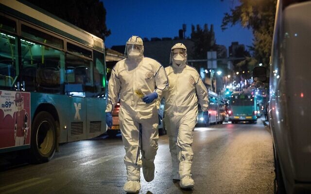 Magen David Adom workers wear protective clothing as a preventive measure against the coronavirus as they arrive to test a patient with symptoms of the COVID-19 disease, in Jerusalem, March 16, 2020. (Yonatan Sindel/Flash90)