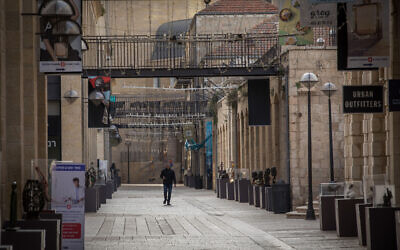 An Israeli man walks past closed stores in the empty Mamila Mall in Jerusalem on March 23, 2020. (Nati Shohat/Flash90)