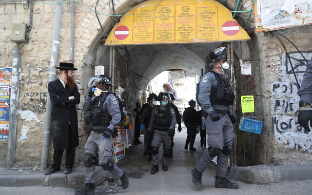 Police officers in the ultra-Orthodox Jewish neighborhood of Mea Shearim in Jerusalem close shops and disperse public gatherings following government orders in an effort to contain the spread of the coronavirus. March 24, 2020. (Yonatan Sindel/Flash90)