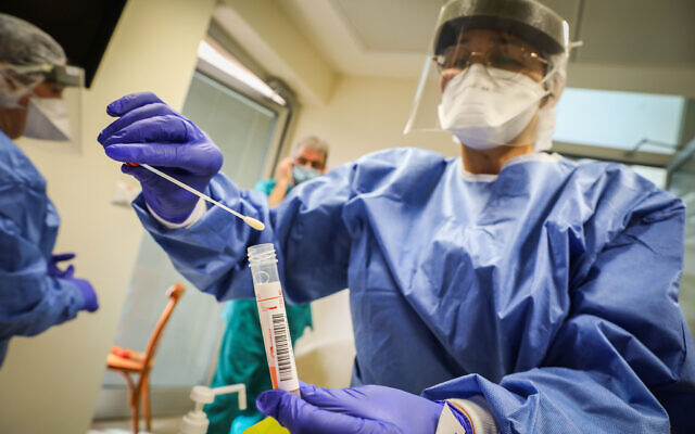 A medical worker in protective gear at Hadassah Hospital Ein Karem in Jerusalem handles a coronavirus test sample on March 24, 2020. (Yossi Zamir/Flash90)