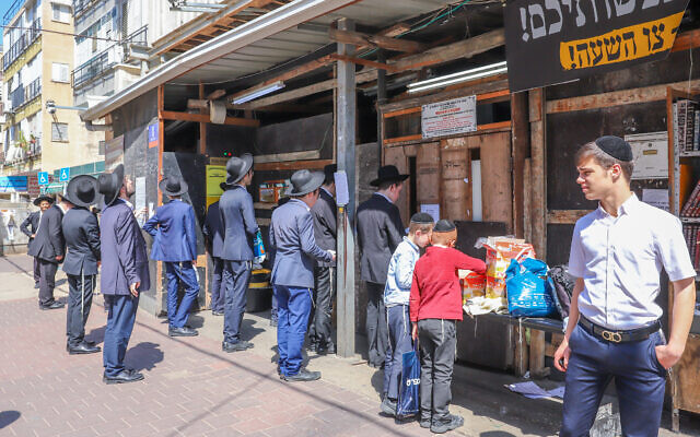 Ultra-Orthodox Jews pray outside a synagogue in Bnei Brak on March 25, 2020. (Yossi Aloni/Flash90)