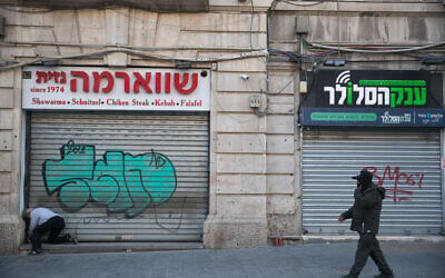 A man passes shuttered stores on Jaffa Street in Jerusalem on March 25, 2020 (Yonatan Sindel/Flash90)
