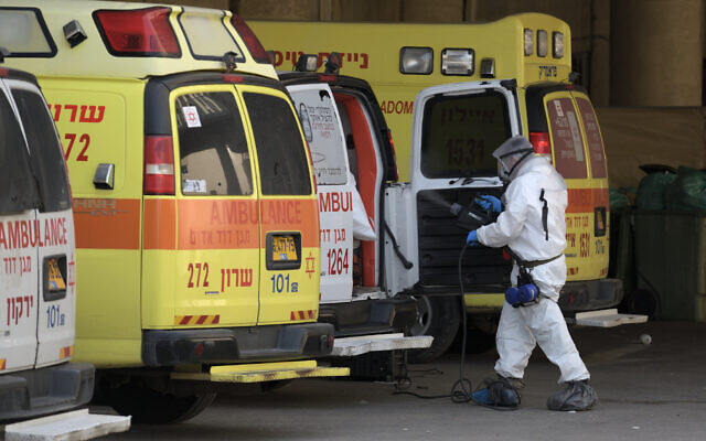Medical personnel cleanse and disinfectian ambulance at Tel Aviv’s Dan Panorama hotel which has been turned into coronavirus quarantine facility, March 26, 2020. (Gili Yaari /Flash90)