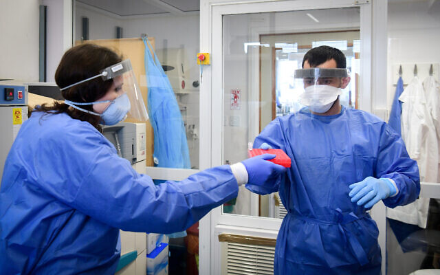 Medical team members at the Barzilay hospital, in the southern Israeli city of Ashkelon, wear protective gear as they handle a coronavirus test sample on March 29, 2020. (Flash90)