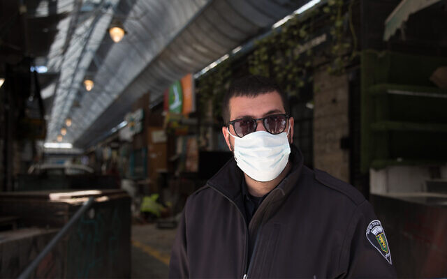 A guard at the shuttered Mahane Yehuda market in Jerusalem, March 29, 2020. (Nati Shohat/Flash90)