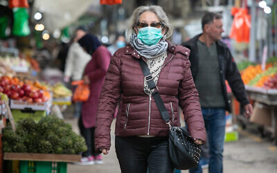 An Israeli woman wears a face mask for fear of the coronavirus while shopping in Ramle, March 19, 2020. (Yossi Aloni/Flash90)