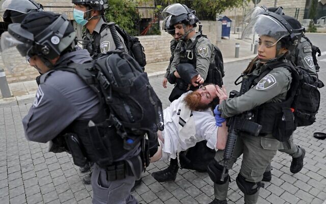 Police arrest an ultra-Orthodox man as they close a synagogue in the Mea Shearim neighborhood in Jerusalem for violating emergency directives to contain the coronavirus, on March 30, 2020. (Ahmad Gharabli/AFP)