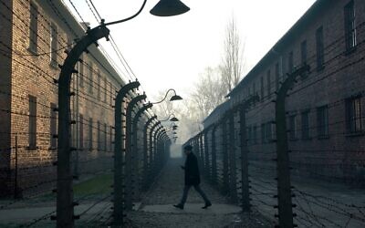 This file photo taken on December 5, 2019, shows a man walking by the barbed wire fence enclosing the memorial site of the former Auschwitz German Nazi death camp. (Janek Skarzynski/AFP)